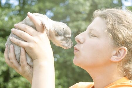 the girl almost gives a kiss to the puppy. on hands. there is toning