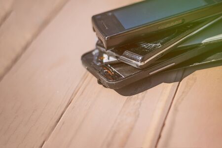 daylight. broken mobile phone. wooden background have toning