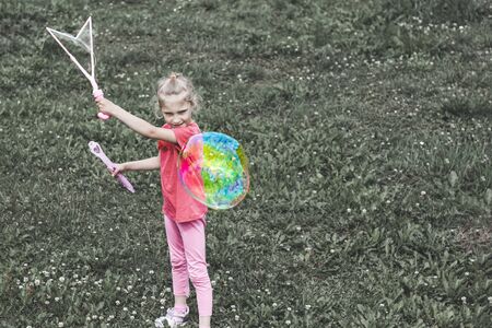 little girl, blonde, playing in the meadow, and blows a bubbleの写真素材