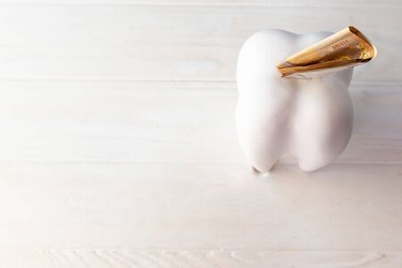 big tooth in the form of a piggy bank. it has the euro. paid dentistry