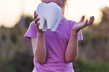 little girl affliction. holds a large plaster tooth. Shallow depth of field.
