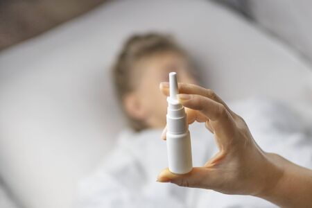 bed. little girl with white hair lies. mom makes an injection in the nose