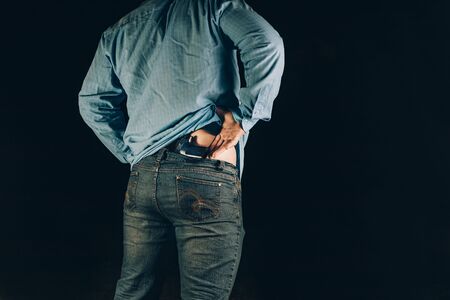 night. a man takes out a gun and prepares to use itの写真素材