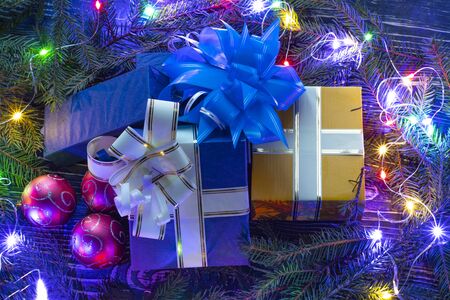 Space. Text. Wooden dark background on it wood texture. Around the Christmas tree legs. Gift boxes with ribbon and bow. There is a Christmas tree decoration.の写真素材