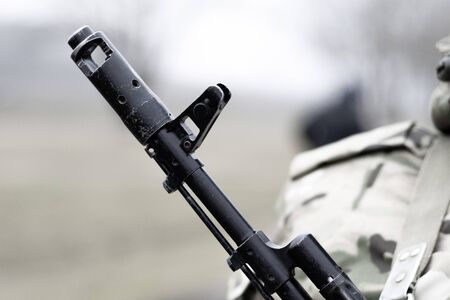 Close-up, assault rifle, on the chest of a military man. There is a tint.