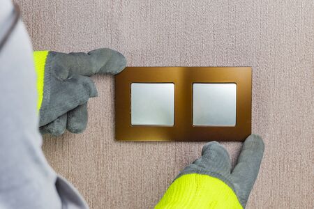 the master electrician sets the switch. Close-up. The room is colored. The switch is brown. The keys...