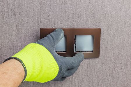 the master electrician sets the switch. Close-up. The room is colored. The switch is brown. The keys...