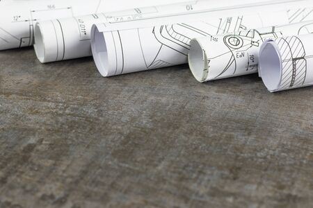 Wooden background. On it are blueprints or a plan of the future home or knowledge. They are rolled...