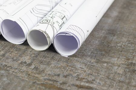 Wooden background. On it are blueprints or a plan of the future home or knowledge. They are rolled...