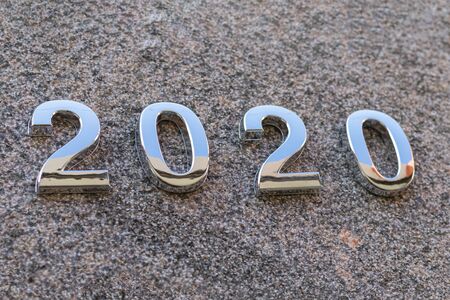 2020 year figures made of metal. Laid out on the stone. Shallow depth of field. There is a tint.
