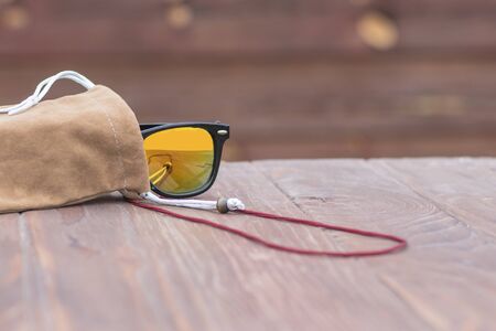 Sunglasses in a protective case. Lie on a wooden background. Shallow depth of field. There is a tint
