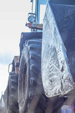 Daylight Yellow loader with a bucket. There is a tint. Close-up.