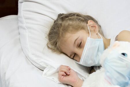 girl with white hair lies in bed. On the face is a medical mask. Close-up.