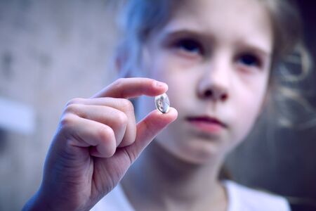 girl on the back Alan, no focus. Holds the pill in his hand in the foreground on it is sharpness. Close-up.の写真素材