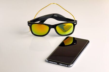 sunglasses and the phone are near, on a white background. No isolation. Close-up.の写真素材