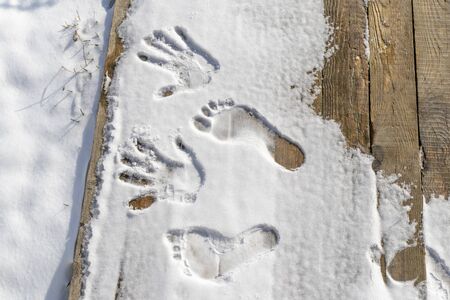 retro style wooden background. The first snow fell on it. Left human footprints of hands and feet.