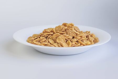 Their flakes are poured a lot. The plate is white. Close-up. The background is not uniform.