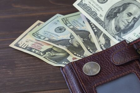 Wooden background in a dark style. On it are banknotes one hundred dollars and one ruble. Exchange...