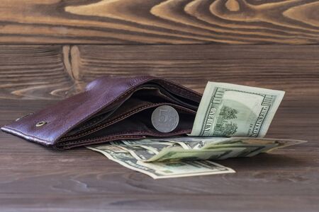 Cinnamon wallet. It has five rubles and next to it are banknotes of one hundred dollars. Foreign currency growth concept.の写真素材