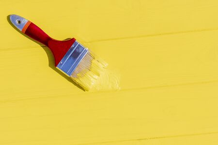 even lighting. Paint brush in yellow. retro style wooden background. Copy space.の写真素材
