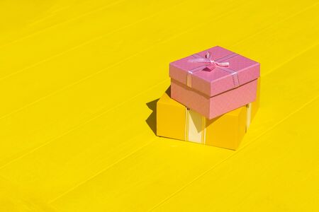 Rough shadow. Bright sunshine. Retro yellow wooden background. Gift box in pink.の写真素材