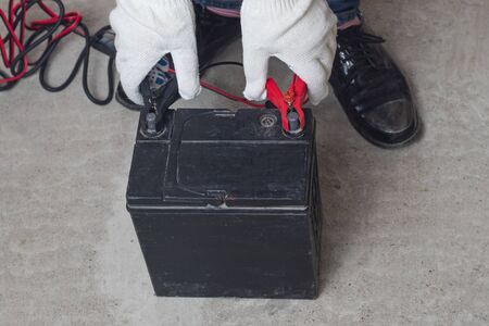 on the concrete floor a flock of car battery, the master puts clips on the terminals for rechargingの写真素材