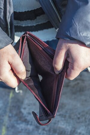 street lighting. Bright sun. A hand opens a wallet and it is empty. Close-up