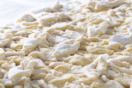 kitchen table. Sprinkled with flour. On it are dough products. Brushwood. Close-up.の写真素材