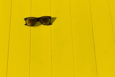 daylight. bright sun. Clear shadows. Wooden background in yellow. He is wearing sunglasses.の写真素材