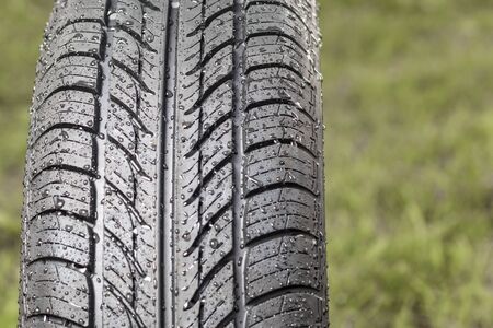 New tire. There are raindrops on it. The tread pattern is looking at us. Close-up
