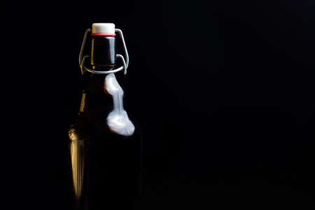 dark lighting. glass bottle close-up. It has a reusable cork made of metal.