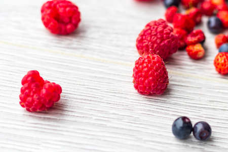 Wood background. Freshly picked blueberries, raspberries and wild strawberries