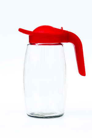daylight. on a white background. Glass decanter with a bright red lid. The concept of replacing polyethylene containers - reusable.の写真素材