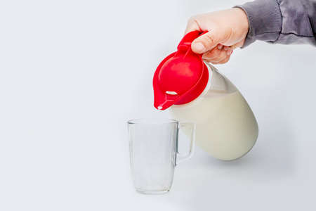 daylight. on a white background in a glass jar milk. The man pours into a mugの写真素材