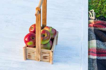 Daylight. a basket of wood with red apples. Retro style white wooden background. Artificially aged.