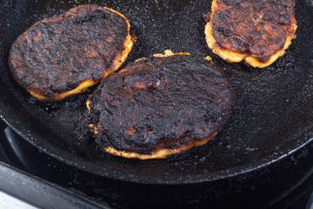 electric stove. Induction. There is a frying pan with food on it. The food is burnt