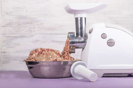 electric white meat grinder. Minced meat is wound and lies in a metal bowl. Copy space. Text.の写真素材