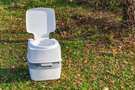 Street lighting. a portable plastic toilet in the foreground. In the back there is a treeの写真素材