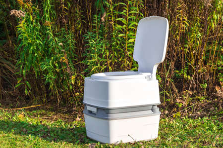 Street lighting. a portable plastic toilet in the foreground. In the back there is a tree