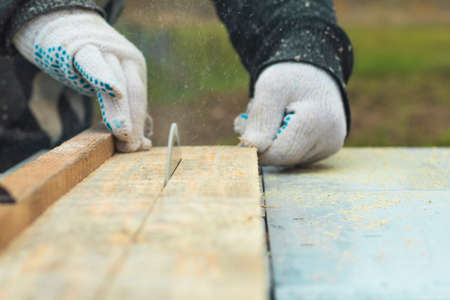Daylight. machine for sawing wood. The master hands the board. Close-up