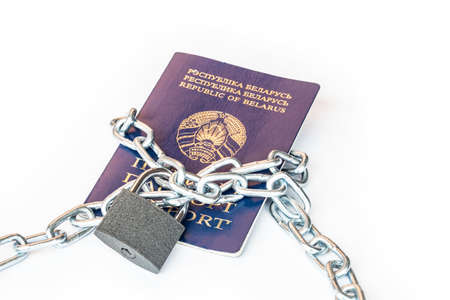 Studio lighting. the citizen's passport is tied with a metal chain in the center with a yellow lock. The concept of violation of the rights of citizens, a ban on movement.の写真素材