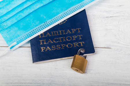 studio lighting. on a wooden background painted white. He is wearing a passport and a medical mask. The document is tied with a metal chain and lockedの写真素材