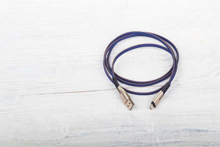 Studio lighting. usb wire for connecting to a computer in blue or purple on a wooden white background in retro style. Close-up.の写真素材