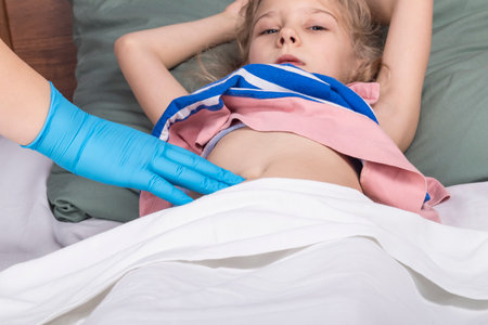 studio lighting. school age girl lies in bed doctor examines the belly. Close-upの写真素材