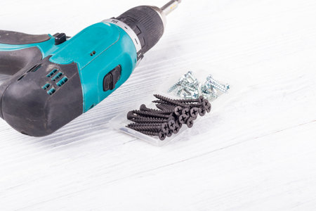 wooden background, retro style, grunge. Green screwdriver and in the box there are black and silver...
