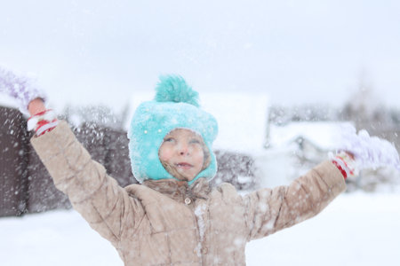 natural light. snowy winter. A child in a winter jacket and a knitted hat throws snow upの写真素材