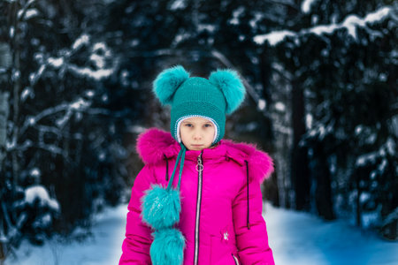 natural light. a girl in a red jacket and a green hat is surrounded by a lot of snow. He looks at...
