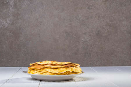 white wooden background in retro style. the plate in it is thin yellow pancakes. close-up