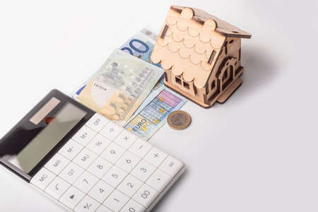 money, euro, wooden toy house, white calculator. the concept of buying and maintaining a house, apartment.の写真素材