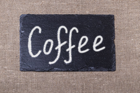 coffee. an inscription on a black stone in white chalk. taken on a burlap bag next to three yellow applesの写真素材
